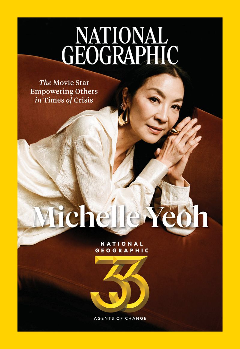 A magazine cover featuring Michelle Yeoh lying on a brown sofa, looking at the camera, with "National Geographic" text.