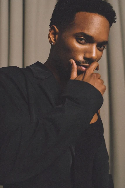 Portrait of a dark-skinned male model in a black blazer against a neutral backdrop, showcasing a stylish and confident aesthetic.