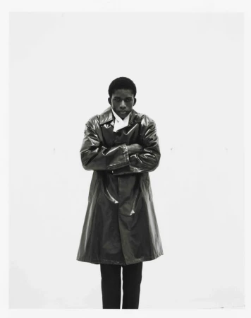 Model Mohammed Banze wearing a glossy dark coat with arms crossed against a white background for The Greatest Magazine.