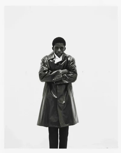 Model Mohammed Banze wearing a glossy dark coat with arms crossed against a white background for The Greatest Magazine.