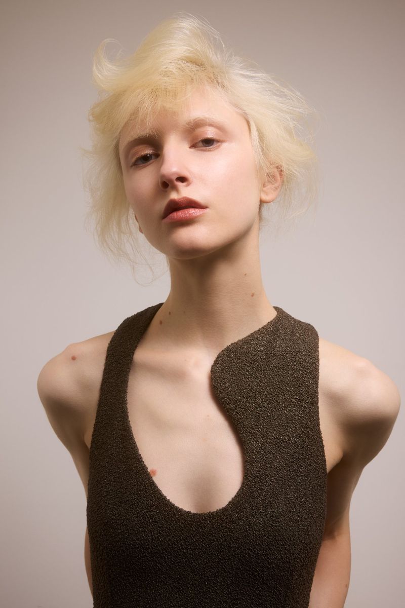 Portrait of a woman with light blonde hair and a dark knit top. Close-up view of the subject, with neutral color grading.
