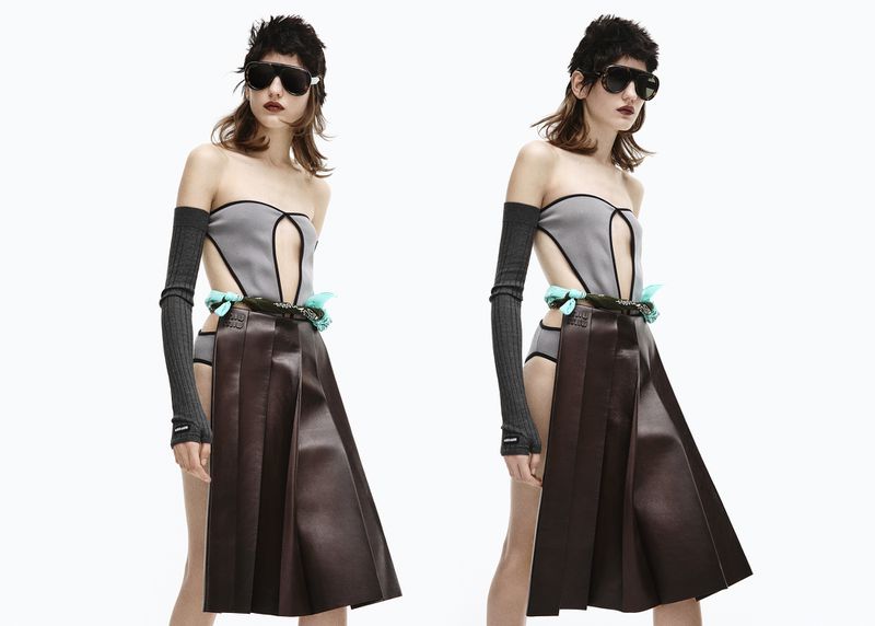 Fashion editorial shot featuring a woman in a grey strapless bodysuit, brown leather skirt, and sunglasses, posing against a white backdrop.