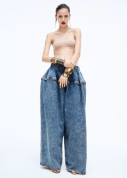Model wearing wide-leg acid wash denim trousers and a strapless bandeau top against a plain white background.