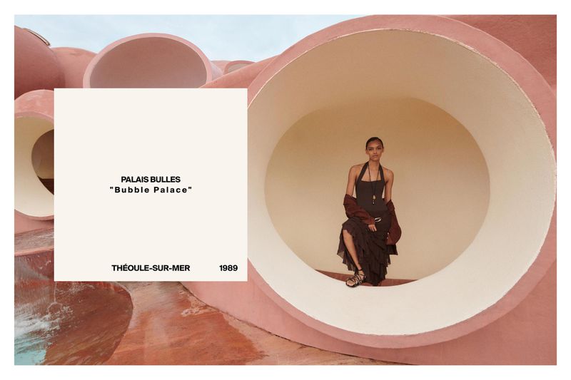 Fashion shot of a Black female model posing in a dark dress inside a large circular opening in Palais Bulles architecture.