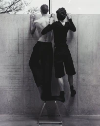 Two young men standing on a chair looking over a concrete wall for Numero Netherlands by photographer Sieme Hermans.