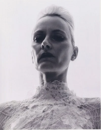 Low-angle monochrome portrait of a model with textured updo wearing a high-necked white lace top