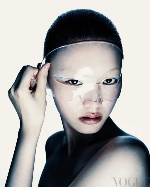 Asian woman with skincare mask. Close-up studio portrait of a female face with a translucent beauty mask and dark hair against bright backdrop.
