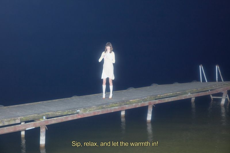 A woman in a white dress stands on a wooden dock at night near the water, against a dark blue sky, with the text overlay.