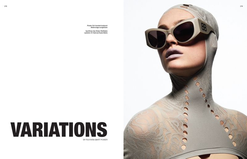 A fair-skinned adult woman with light lipstick wears sunglasses and a high-necked bodysuit with oval cutouts in a studio shot.