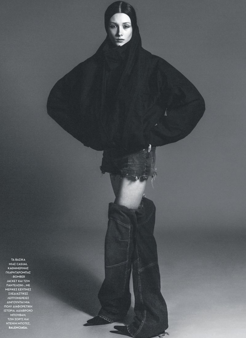 A full-length studio shot captures a fashion model in a black hooded jacket, denim mini skirt, and deconstructed denim boots against a grey backdrop.