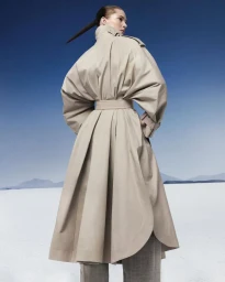 Model Iselin Steiro wearing a belted beige trench coat against a desert salt flat and blue sky for Mastermind Magazine.
