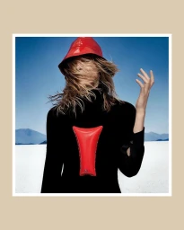 Model Iselin Steiro wearing a red hat and black top against a bright horizon in a Mastermind Magazine editorial photograph.