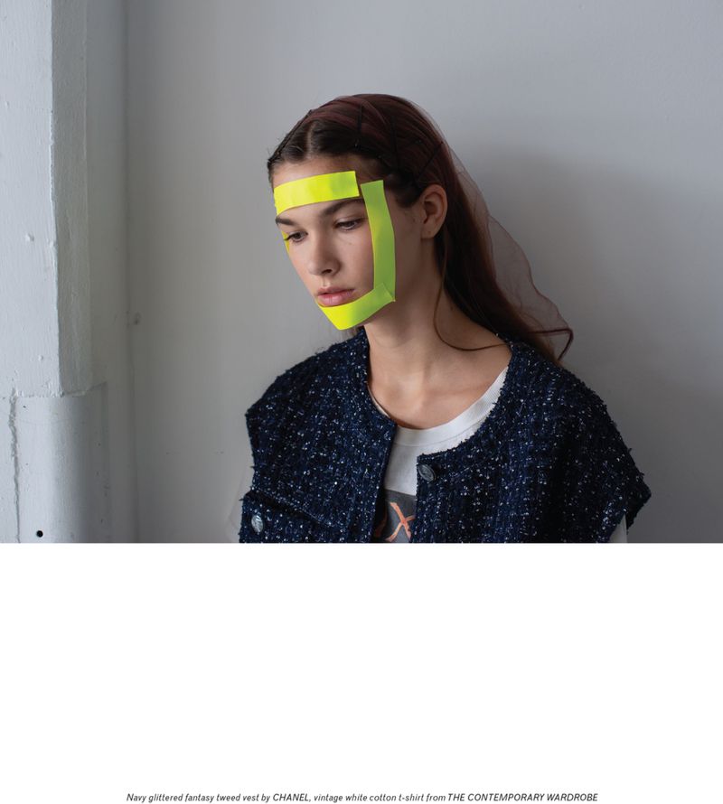 Model wearing a navy tweed vest and neon tape in a studio with natural lighting. Fashion editorial style. Studio shot with copy space.