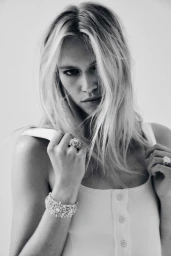 Model Nikki Mcguire wearing a white tank top and diamond jewellery against a plain white background