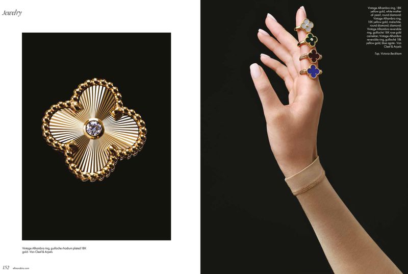 Close-up of a woman's hand with clover-shaped rings and a clover-shaped gold pin with diamond on a black background. Jewelry.