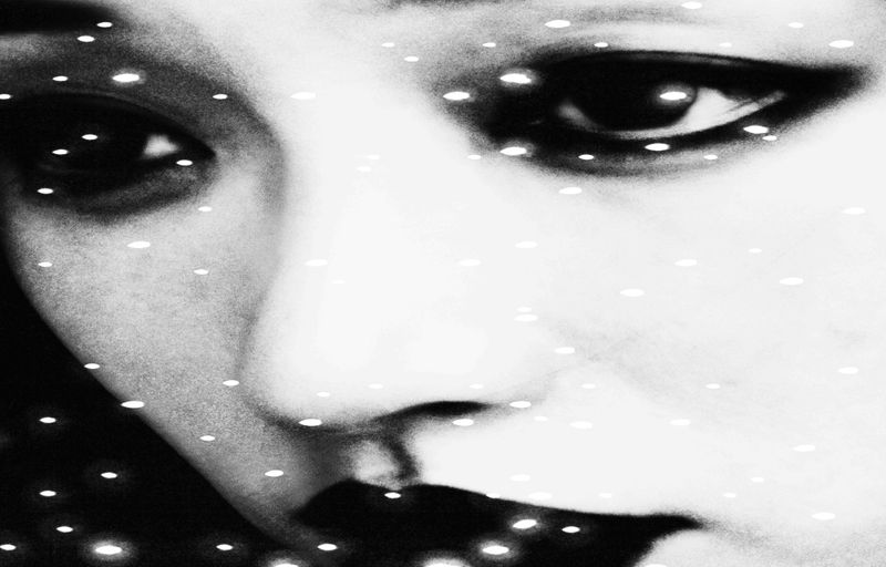 Dramatic black and white close-up of a human face with an intense stare, contrasted with sparkling bokeh effects for added depth.