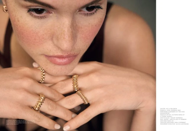 Close-up of a fair-skinned woman with freckles and wearing gold rings. Focus on the woman's face, complexion, and fashion jewellery.