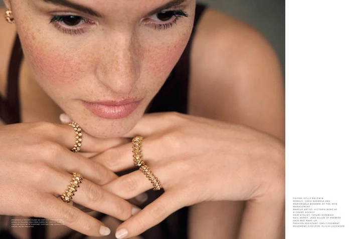 Close-up portrait of a model with freckles wearing gold studded rings and earrings, shot by Silvia Draz for Mojeh Magazine.