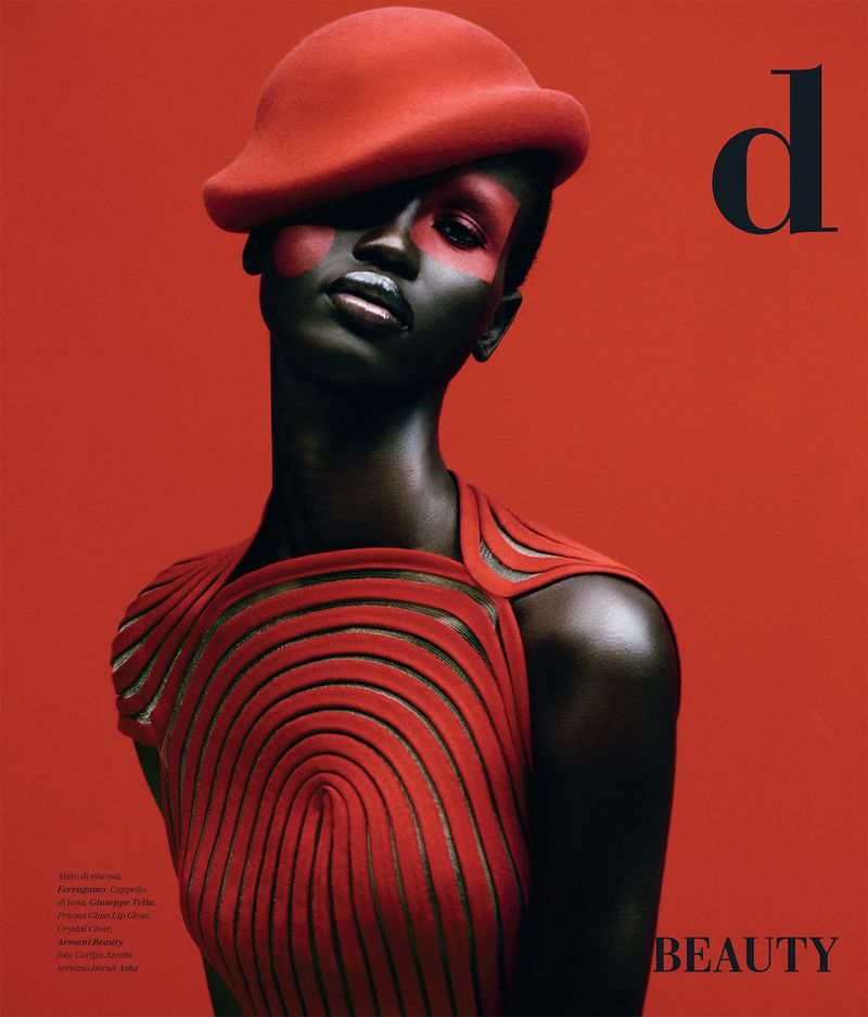 Fashion magazine cover featuring a Black woman with dark skin wearing a red hat and a red sleeveless dress on a solid red backdrop.