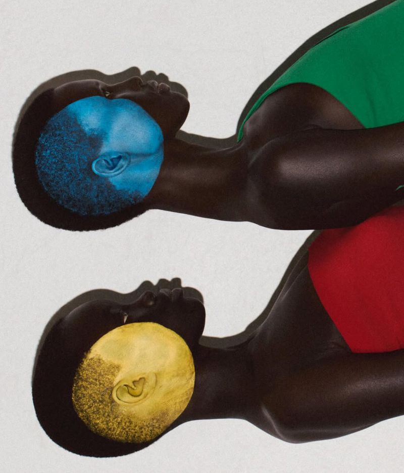 Two African American figures overlap, with one wearing a green swimsuit and a blue-colored head, and the other in red with a yellow head.