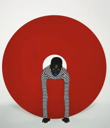 Model in striped top leaning forward through a large red and white circular set piece against a white background.