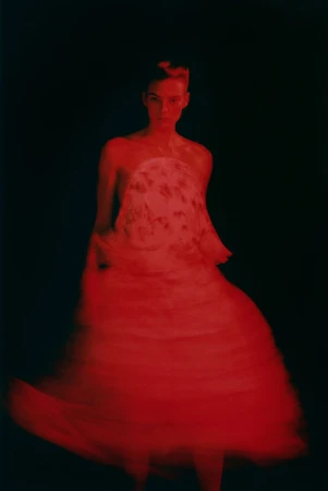 Model Beauïse Genç wearing a vibrant red dress against a dark background for Exhibition Magazine Ti Amo editorial.