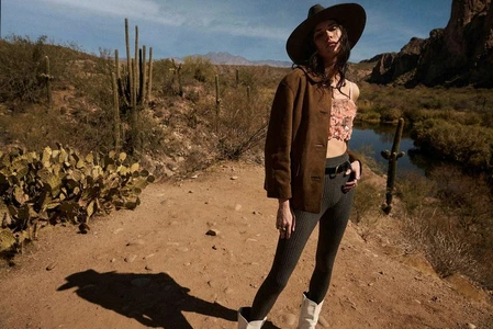 Model Vanessa Moody in desert landscape wearing a brown jacket, hat, and patterned top for Madame Figaro.
