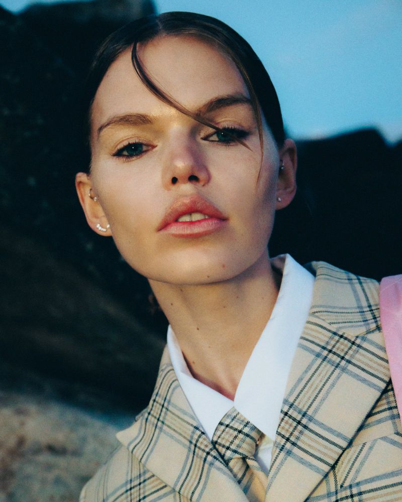Close-up portrait of a female model wearing a plaid blazer and matching tie outdoors