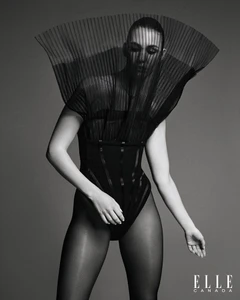 Model wearing a black pleated fan-like headpiece and dark bodysuit for an Elle Canada editorial portrait.