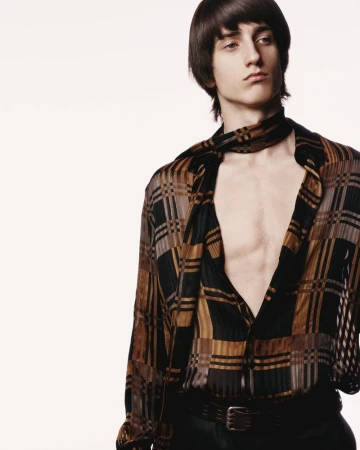 Model wearing a plaid silk shirt and matching scarf against a plain light background