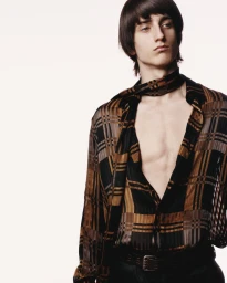 Model wearing a plaid silk shirt and matching scarf against a plain light background