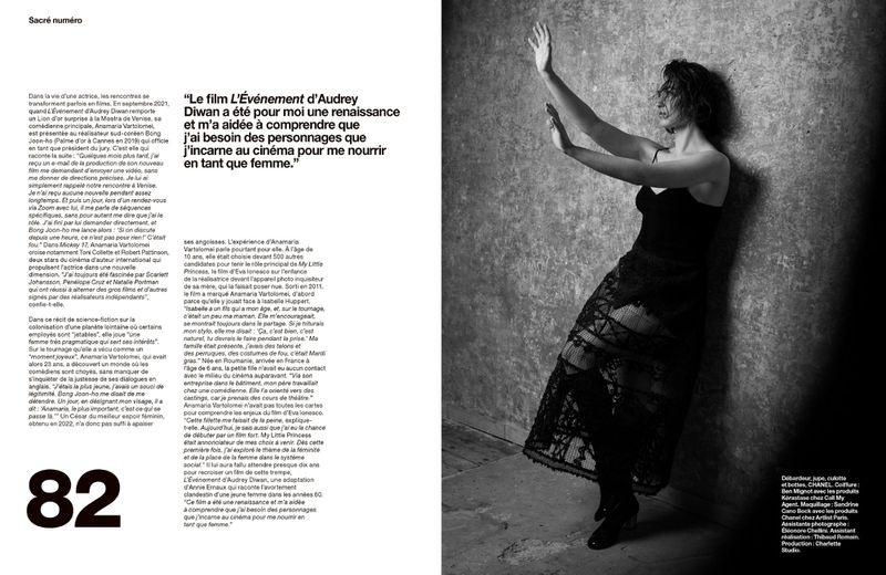 Black and white portrait of a woman in a lace dress leaning against a textured wall with her hands raised, studio lighting.