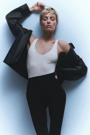 Wallis Day wearing a white tank top and black leather jacket against a light grey seamless backdrop for Numero Netherlands.