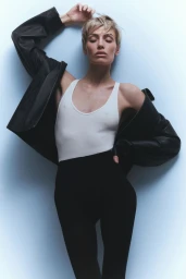 Wallis Day wearing a white tank top and black leather jacket against a light grey seamless backdrop for Numero Netherlands.