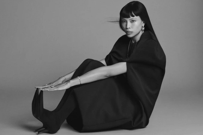 Model Diane Chiu wearing a dark oversized outfit and high heels seated against a grey studio backdrop for Pop Magazine.