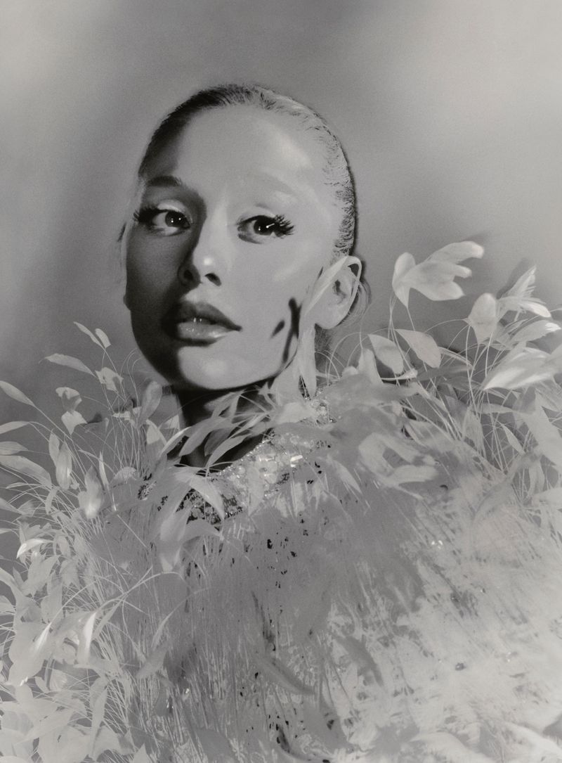 Monochrome portrait of a young woman, fair skin, with a light feather boa, gazing at the viewer, eye-level angle, and clean background.