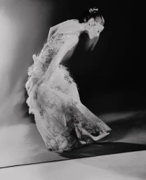 Ariana Grande in a feathery white gown posing dramatically in a monochrome fashion editorial by Elizaveta Porodina for Vogue Italia.