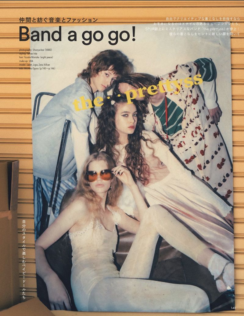 Editorial image on a poster featuring three fashion models posing indoors in vintage clothing with neutral colors and studio lighting.