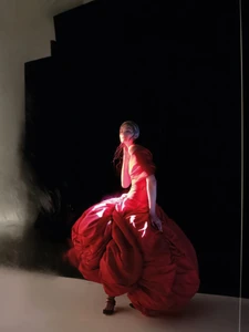 Model Lulu Tenney in a voluminous red gown posing against a dark abstract backdrop for Harper's Bazaar Italia by Nick Knight