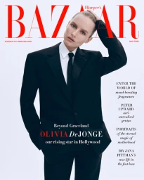 Model wearing a black suit and tie against a white background for a magazine cover shoot with red typography