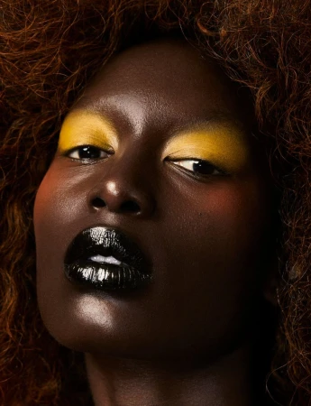Portrait of a dark-skinned woman with afro and yellow eyeshadow, wearing black lipstick. Close-up shot emphasizing beauty and makeup.
