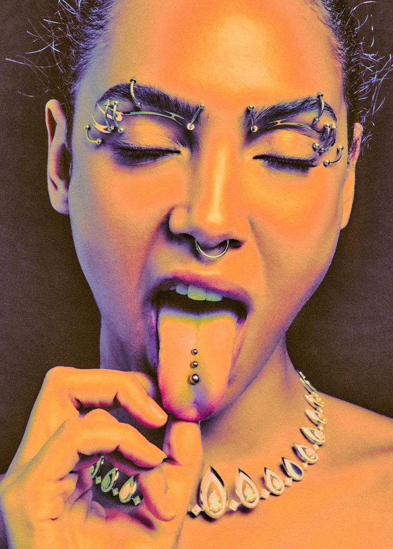 Adult woman with piercings sticking out her tongue, wearing a jeweled necklace. The model is set against a dark background.