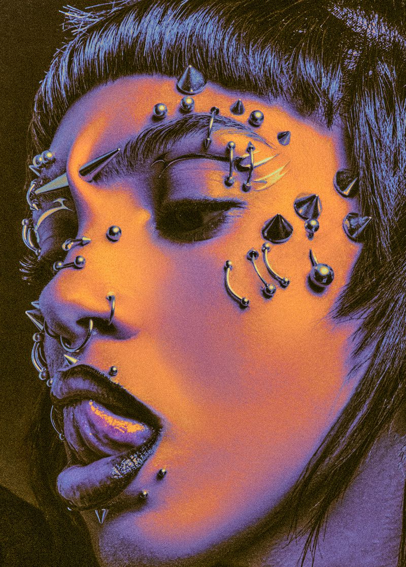 Close-up portrait of a person with numerous face piercings, vibrant orange and purple skin tones, and dark hair against a dark background.