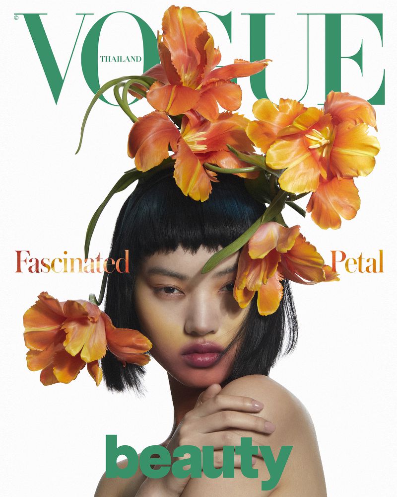 Vogue Thailand magazine cover featuring an Asian female model with orange flowers, makeup, and short black hair against a white background.