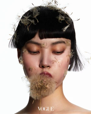Close-up portrait of model Wenqing Liu with dandelion seeds on her face and dark bob hair for Vogue Thailand Flora-Vaganza.