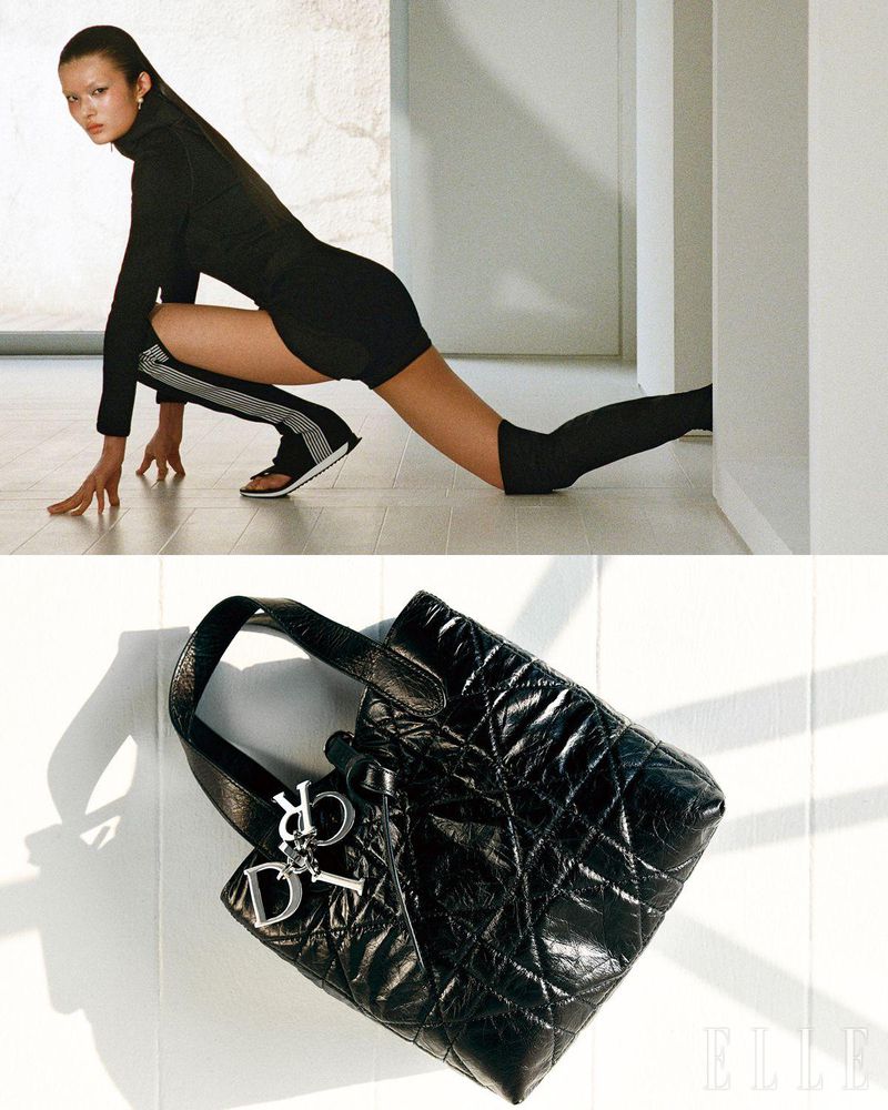 Woman in athletic pose with black quilted leather purse and silver Dior charm. Indoor shot with neutral wall, tiled floor.