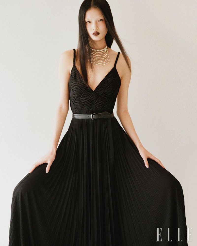 Elegant portrait of Asian woman in black gown and pearl necklace. Fashion editorial shot with sophisticated, dark lipstick.