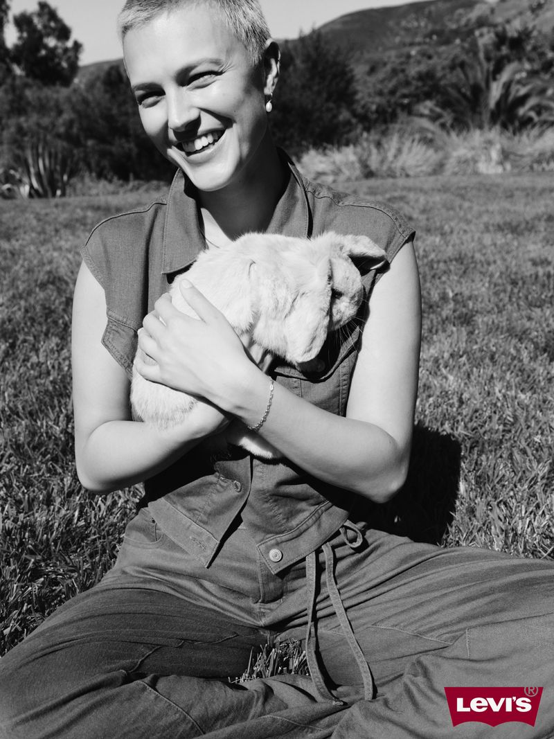 Monochrome portrait of a smiling woman with short hair holding a rabbit outdoors on grass for Levi's 2025 campaign.