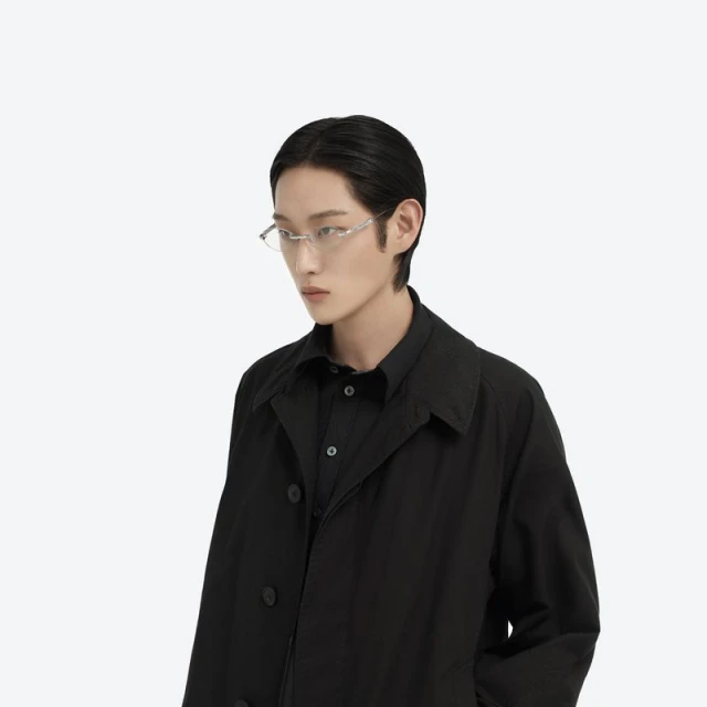 An Asian adult male model in a black trench coat and silver rim glasses poses in a neutral eye-level shot against a white background.