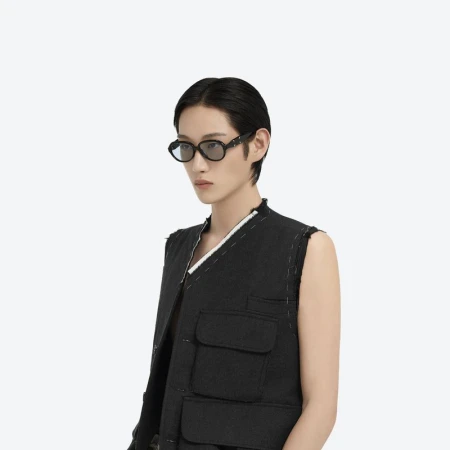 Model wearing dark sunglasses and black vest against a plain white background for Maison Margiela and Gentle Monster